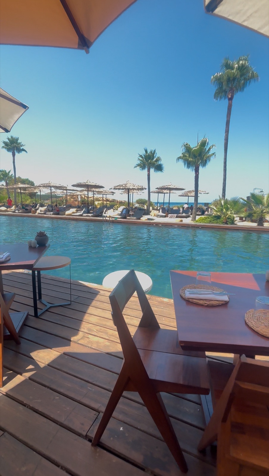 The long heated pool at Domes Zeen Chania with loungers and umbrellas on gravel