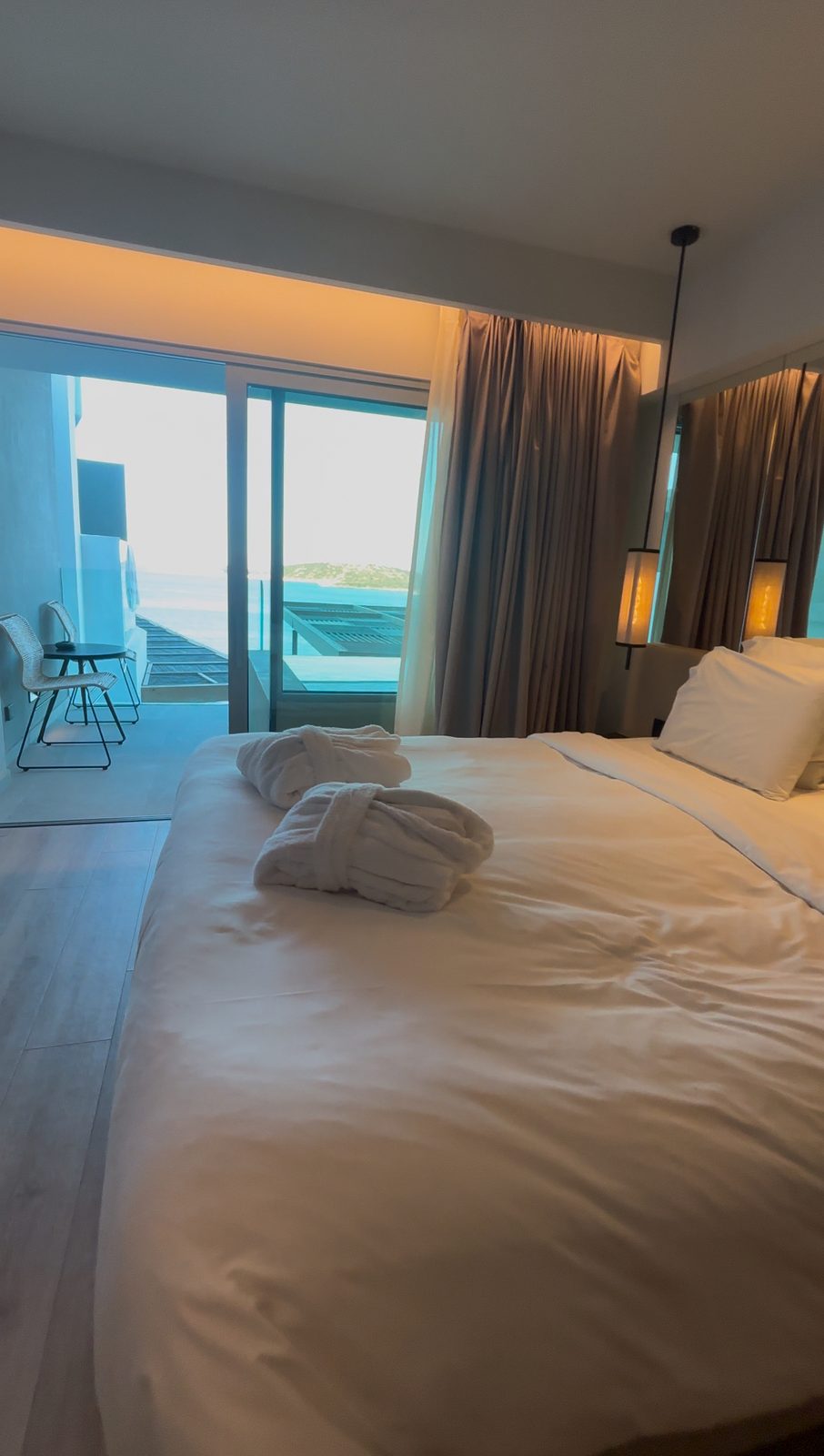 The sixth floor upgrade: bed, glass wall, plunge pool, then Mirabello Bay.